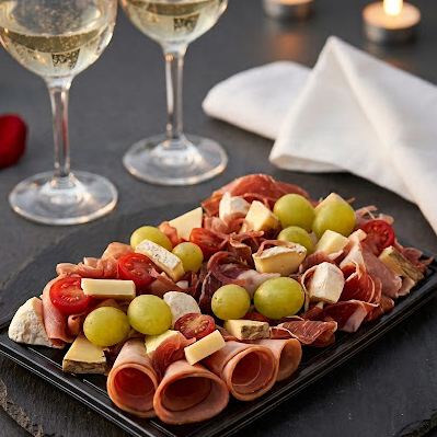 Gros plan du plateau repas pour deux : charcuterie, fromage et raisins